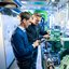 Zwei Mitarbeitende stehen im Prüfbereich der Kälte-, Klima- und Lüftungstechnik bei TÜV NORD und blicken auf technische Geräte, die sie in den Händen halten.