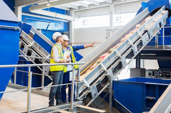Zwei Personen besichtigen eine Recyclinganlage zur Abfallwirtschaft