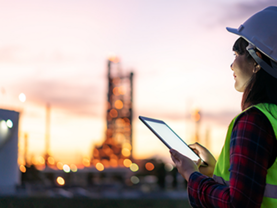 Employees in protective clothing in front of an industrial plant at dusk – symbolic image for the law on financing the energy transition in the electricity sector