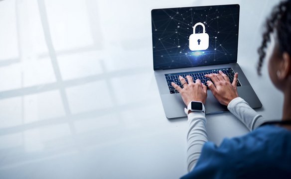 Person tippt auf Laptop mit eingeblendetem Sicherheitsschloss-Symbol auf dem Bildschirm.