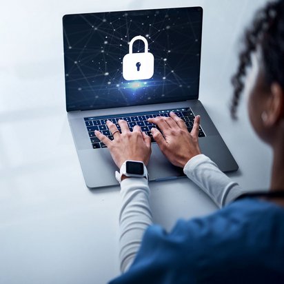 Person tippt auf Laptop mit eingeblendetem Sicherheitsschloss-Symbol auf dem Bildschirm.