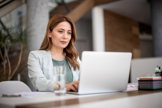 Frau arbeitet an einem Laptop am Schreibtisch
