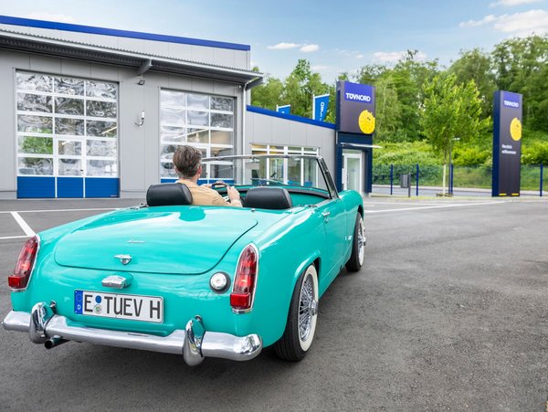 Klassischer grüner Oldtimer vor einer TÜV NORD Station