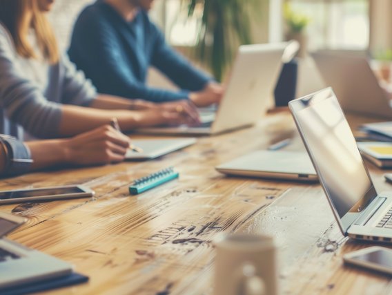Teilnehmende arbeiten in einer Schulungssituation mit Laptops und Unterlagen – Fokus auf Energie- und Klimathemen