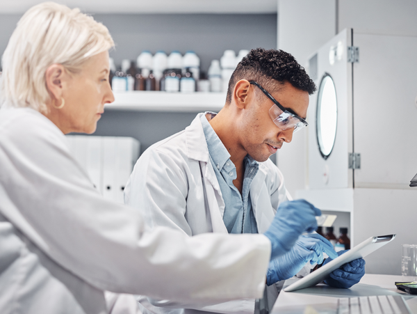 Ein Wissenschaftsteam arbeitet gemeinsam in einem Labor, betrachtet Daten auf einem Tablet