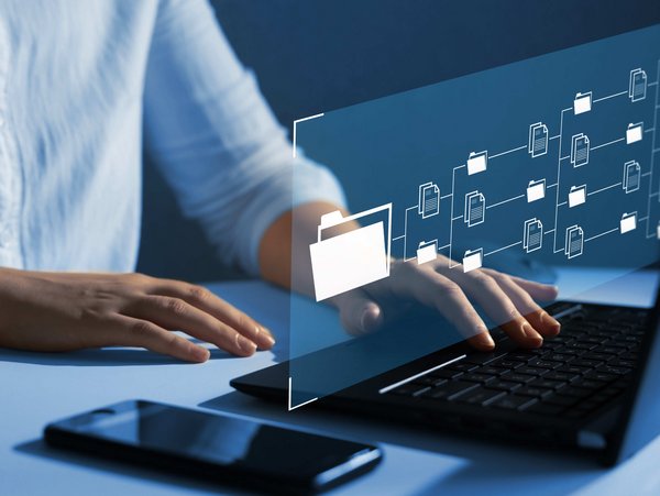 Person tippt auf Laptop mit schwebendem Interface aus Ordner- und Dokumentensymbolen.