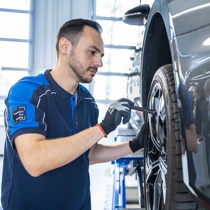 TÜV NORD Mobilität – Fahrzeugprüfung durch erfahrene Prüfingenieure Prüfingenieur von TÜV NORD Mobilität überprüft ein Fahrzeug an einer Hebebühne in einer Prüfstelle.