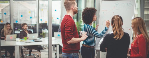 Team entwickelt gemeinsam Ideen an einem Whiteboard in einem modernen Büro.