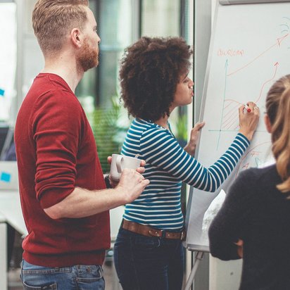 Team entwickelt gemeinsam Ideen an einem Whiteboard in einem modernen Büro.