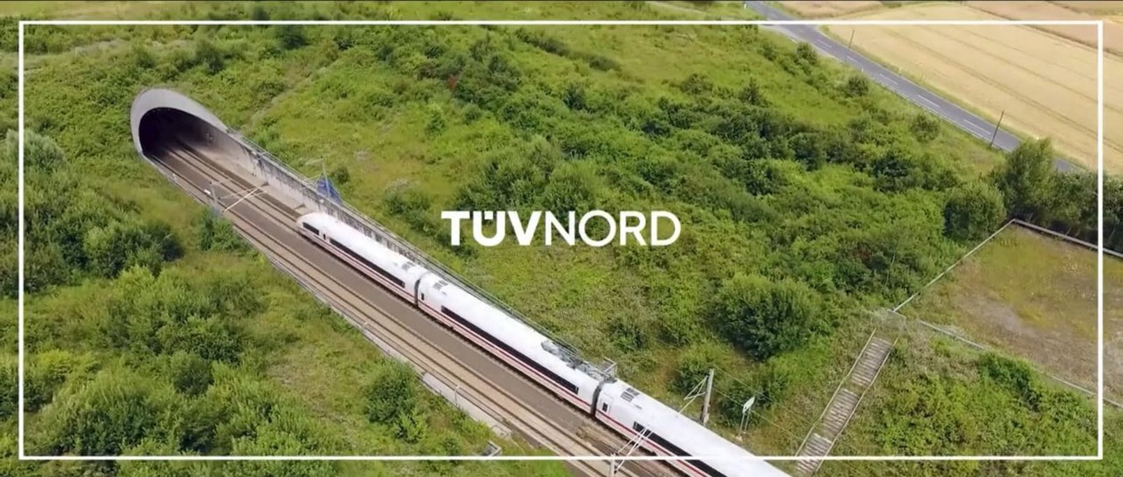Hochgeschwindigkeitszug verlässt Tunnel in grüner Landschaft