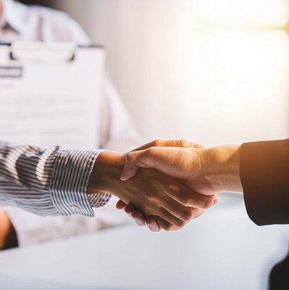 Handschlag bei Vertragsunterzeichnung für einen Job durch die TÜV Transfer Jobvermittlung.