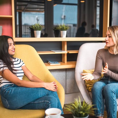 Zwei Frauen sitzen in Sesseln und unterhalten sich in entspannter Atmosphäre