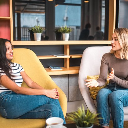 Zwei Frauen sitzen in Sesseln und unterhalten sich in entspannter Atmosphäre