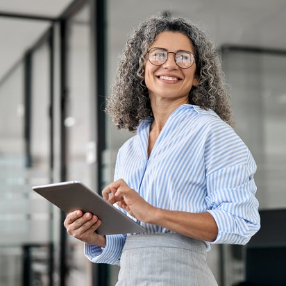 Ein Projektmanager steht in einem modernen Büro und bedient ein Tablet.