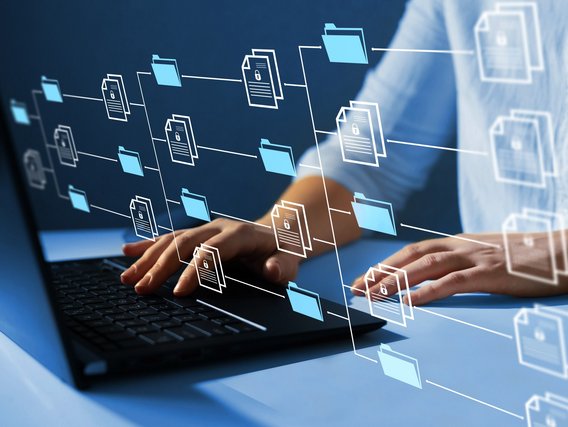 Hände tippen auf einer Laptop-Tastatur, umgeben von schwebenden digitalen Ordner- und Dokumentensymbolen.