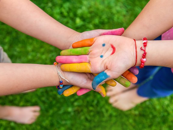 Bunt bemalte Kinderhaende die ein Lächeln zeigen_und_aufeinander_liegen