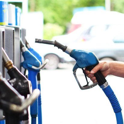 Hand hält Zapfpistole an einer Tankstelle