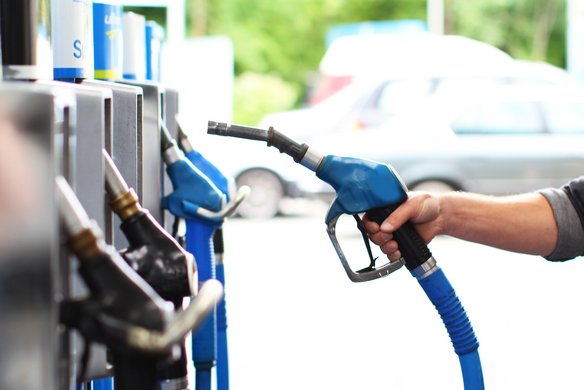 Hand hält Zapfpistole an einer Tankstelle