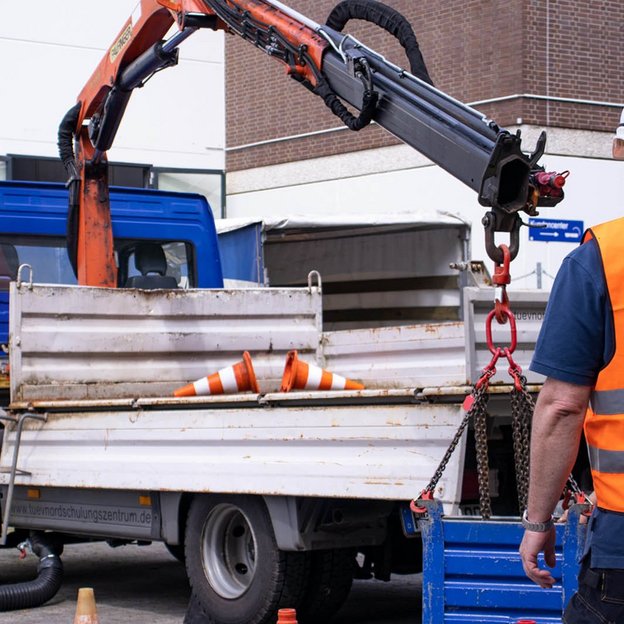 Arbeiter in Sicherheitskleidung bedient einen LKW-Ladekran bei einer Schulung.