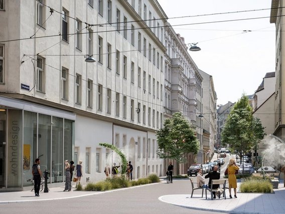 Eine verkehrsberuhigte Fußgängerzone mit historischen Gebäuden, modernen Geschäften und Menschen, die zwischen Bäumen und Sitzbereichen flanieren.