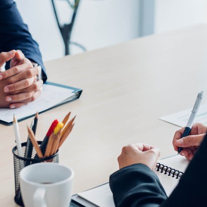 Hände zweier Menschen auf einem Schreibtisch während eines Gesprächs zum Übergang in zivile Jobs, unterstützt von TÜV NORD Transfer.