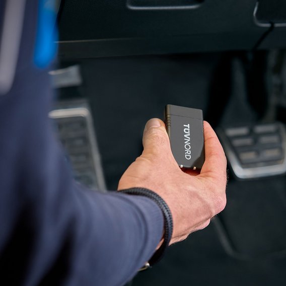Prüfingenieur hält TÜV NORD Onboard Diagnose im Fahrzeug