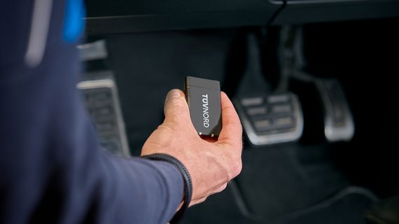 Prüfingenieur hält TÜV NORD Onboard Diagnose im Fahrzeug
