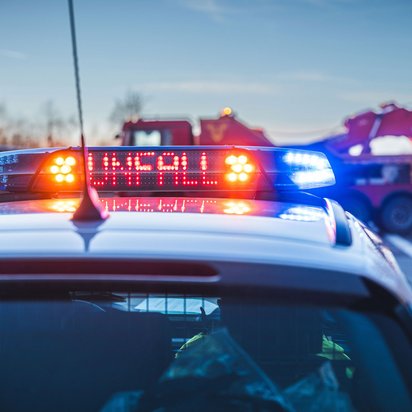 Polizeifahrzeug mit eingeschaltetem Blaulicht und Unfallwarnung