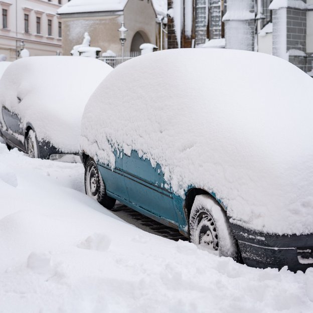 Autos unter einer dicken Schneedecke in einer Stadt
