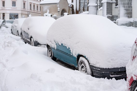Autos unter einer dicken Schneedecke in einer Stadt
