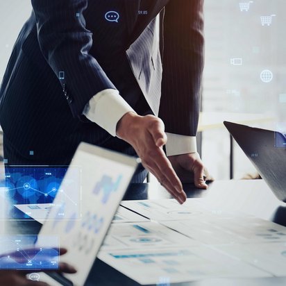 Geschäftspersonen in Besprechung mit Laptops und digitalen Datenvisualisierungen.