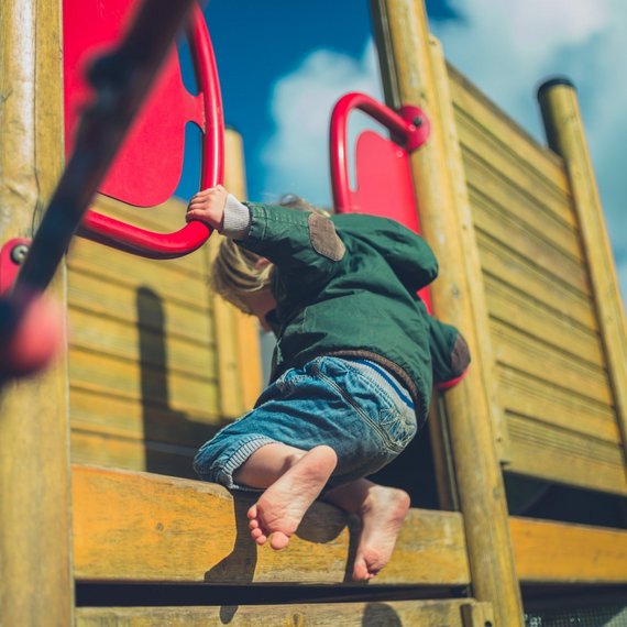 Ein Kind klettert barfuß auf ein Spielgerät.