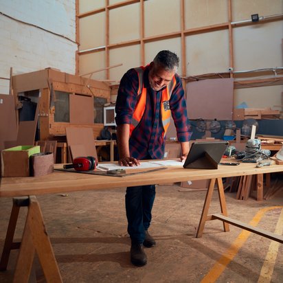 Ein Mann in Schutzkleidung stützt sich auf einen Tisch und prüft Unterlagen zur Bauprodukteverordnung.