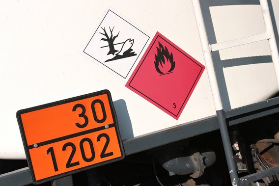 Gefahrgutkennzeichnung auf einem Transportfahrzeug mit Symbolen für Umweltgefahr und entzündbare Flüssigkeiten.