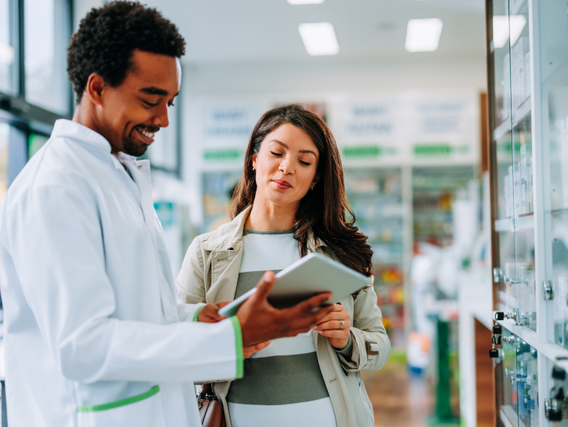 Apotheker informiert Kundin mit einem digitalem Tablet