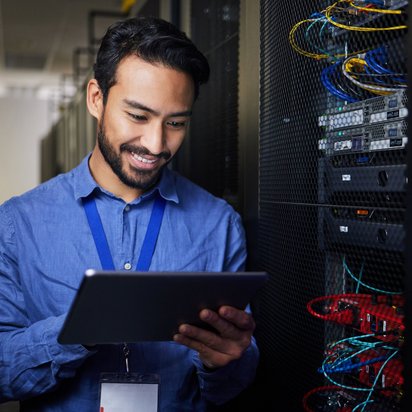 Systemüberwachung und Wartung im Rechenzentrum mit digitaler Unterstützung. IT-Techniker prüft mit Tablet die Systeme in einem Rechenzentrum.
