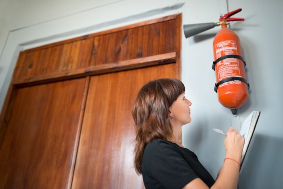 Frau überprüft Feuerlöscher