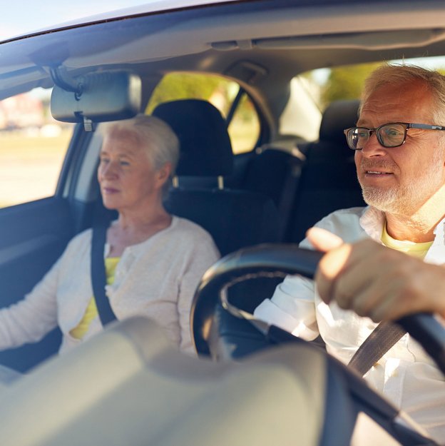 Seniorenpaar fährt im Auto auf einer sonnigen Straße