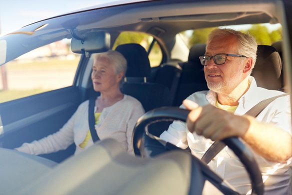 Seniorenpaar fährt im Auto auf einer sonnigen Straße