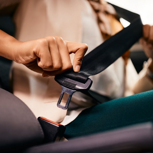 Nahaufnahme einer Person, die sich im Auto mit dem Sicherheitsgurt anschnallt