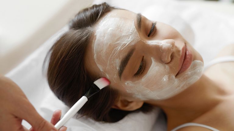 Facial Beauty Treatment. Beautiful Woman Getting Cosmetic Mask